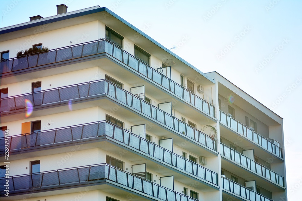  Fragment of a facade of a building with windows and balconies. Modern home with many flats.