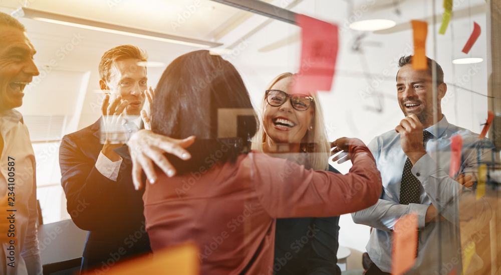 Businesswomen hugging while brainstorming with their team in an