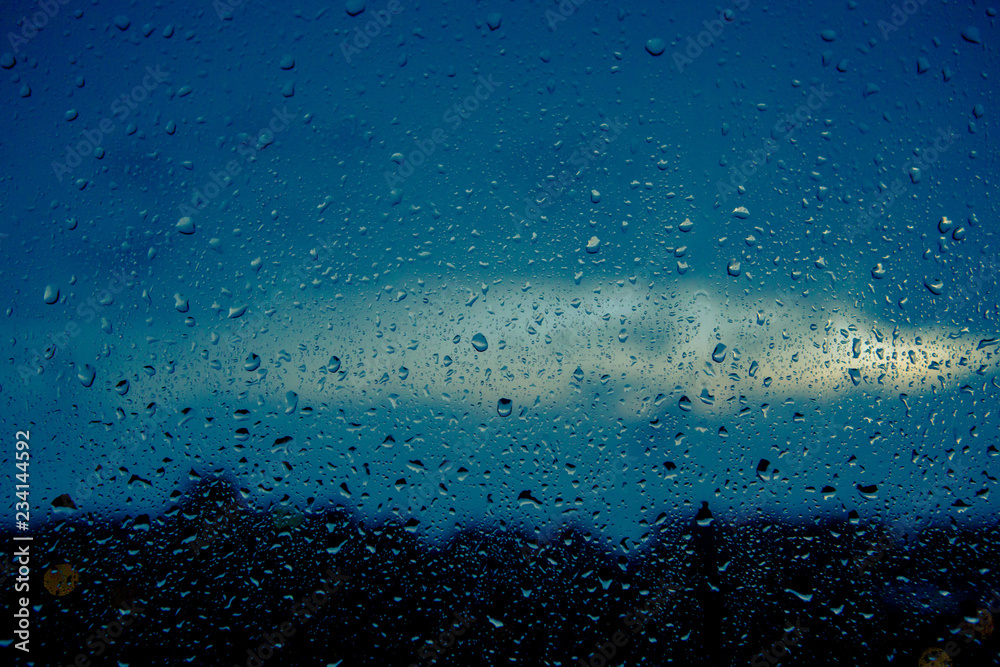 窗户上的雨滴特写。雨天窗户玻璃上移动的雨滴背景。