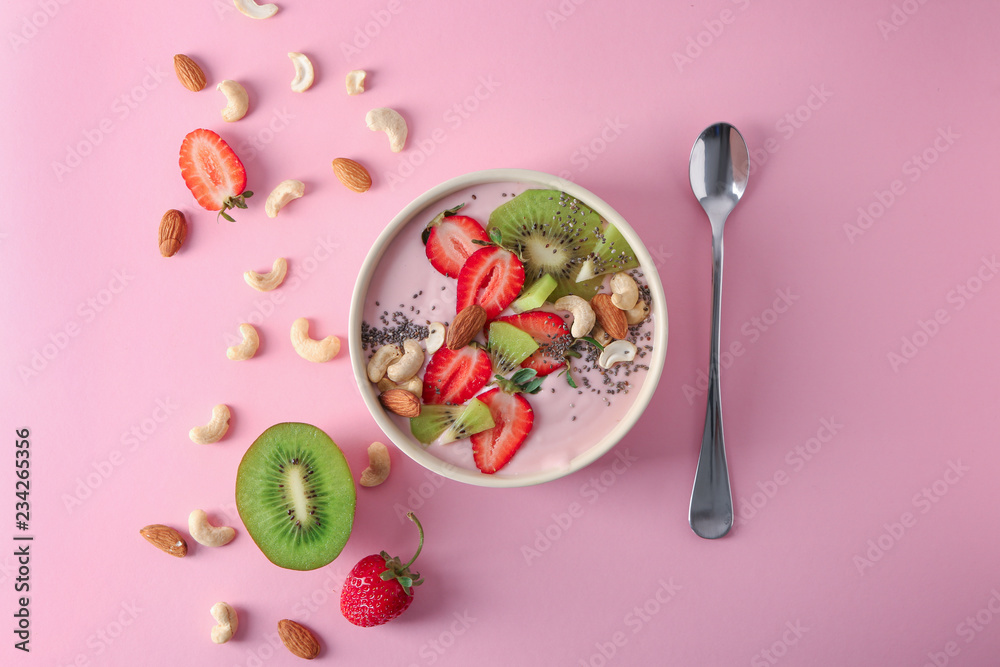 Bowl with pink yogurt and fresh fruits on color background