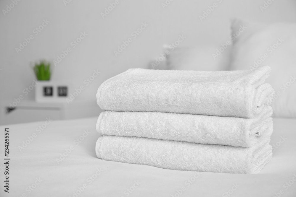 Folded white soft towels on bed indoors