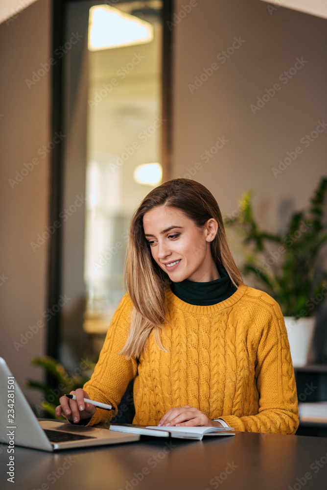 Casual business woman working with laptop and notebook.