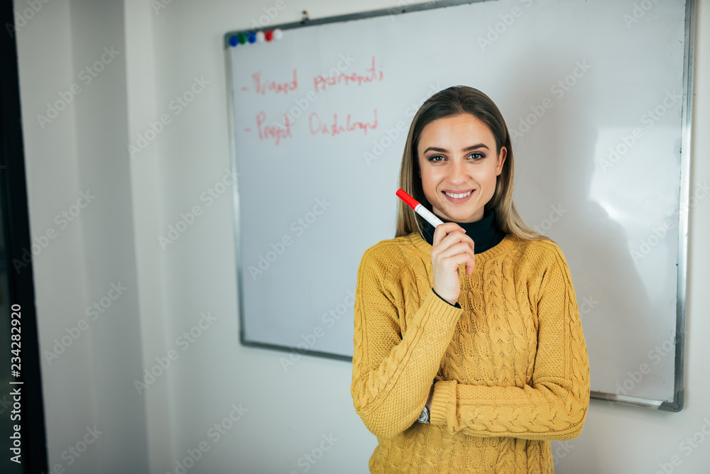 一位年轻女子站在白板前拿着马克笔的肖像。