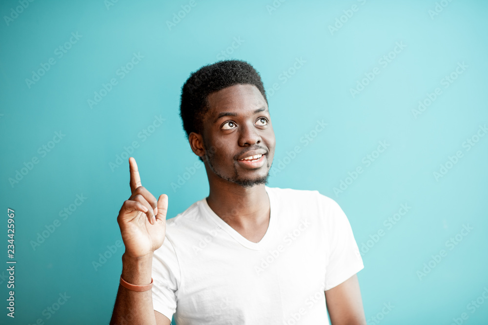 Portrait of a young african man dressed in white t-shirt having an idea on the colorful background