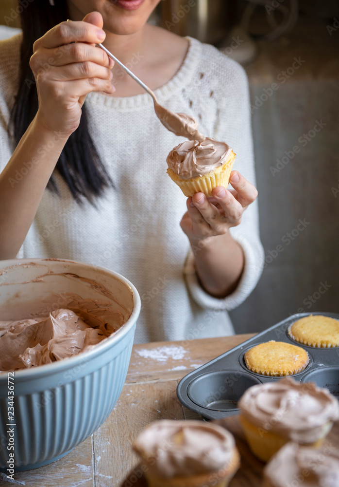 在纸杯蛋糕食品摄影食谱创意中添加巧克力糖霜的女人