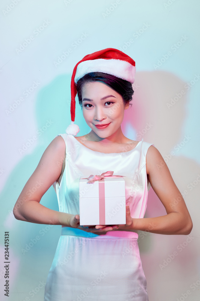 Happy excited young woman in santa claus hat with gift box over light background