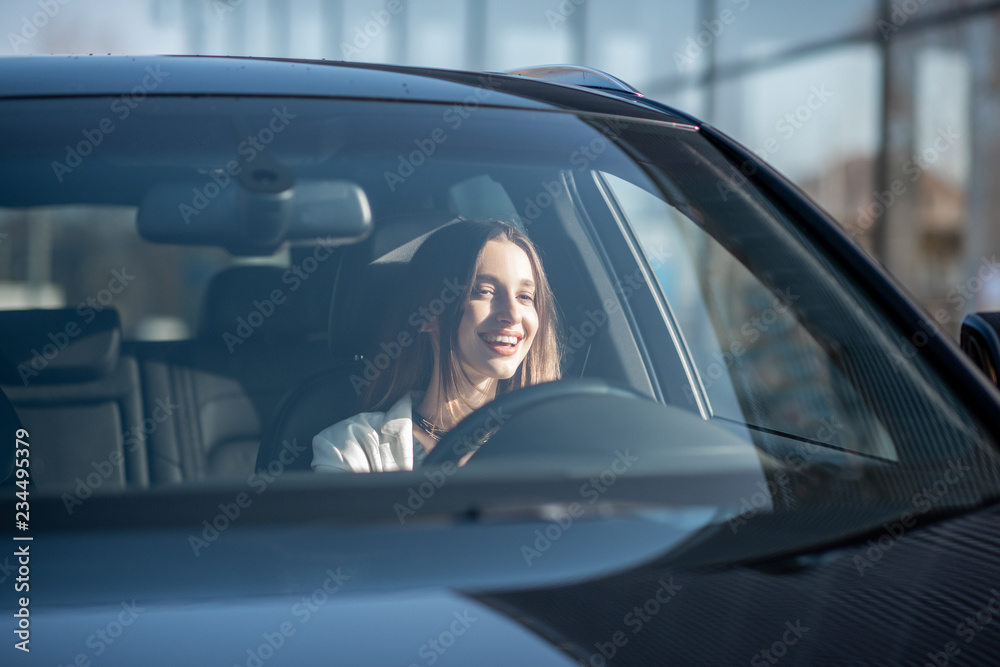 年轻的女商人开着豪车，从外面透过挡风玻璃看