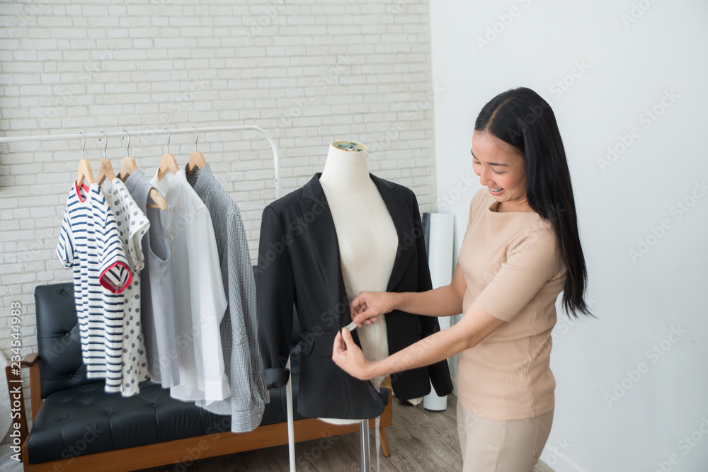 Young Asian professional  fashion designer or dressmaker measuring a women suit and dress. beauty an