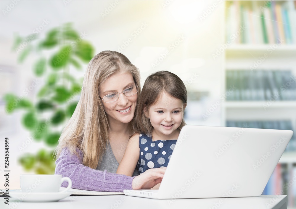 Beautiful mother and cute daughter using laptop