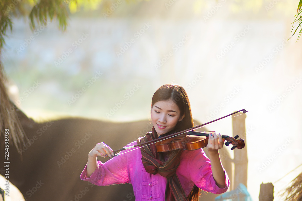 Music,melody,song concept. Asian beautiful girl playing a violin with happiness. Women enjoy playing