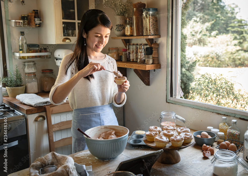 在纸杯蛋糕食品摄影食谱创意中添加巧克力糖霜的女人