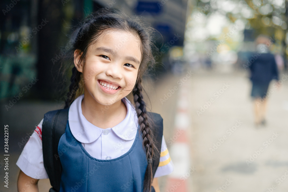 回到学校。校园里的快乐微笑的小学女孩。