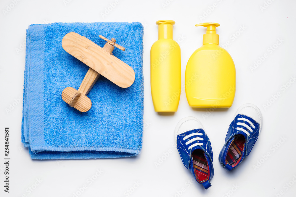 Towel with baby cosmetics, booties and toy on white background