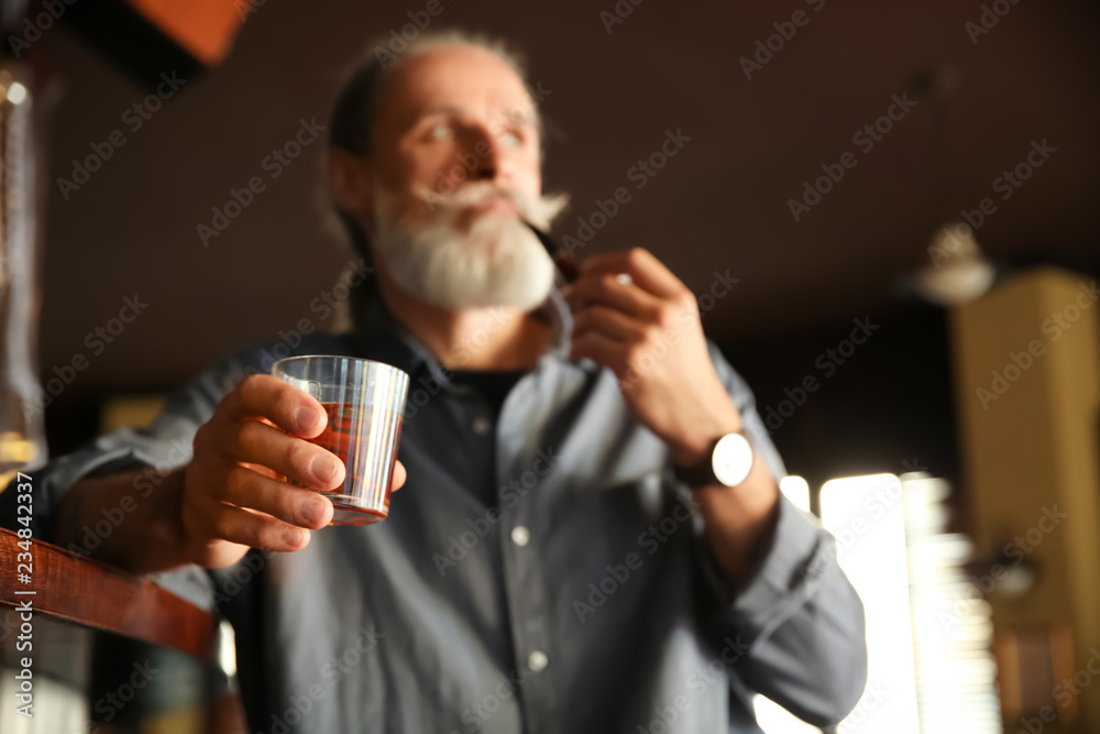 酒吧里拿着一杯威士忌和烟斗的老人