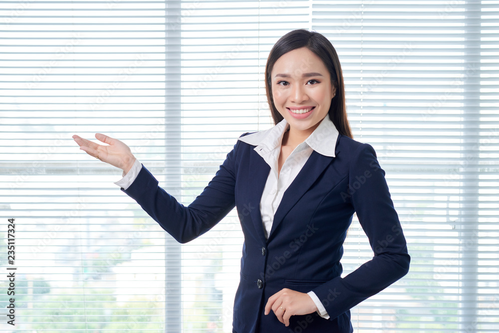 Smiling asian businesswoman standing in bright office