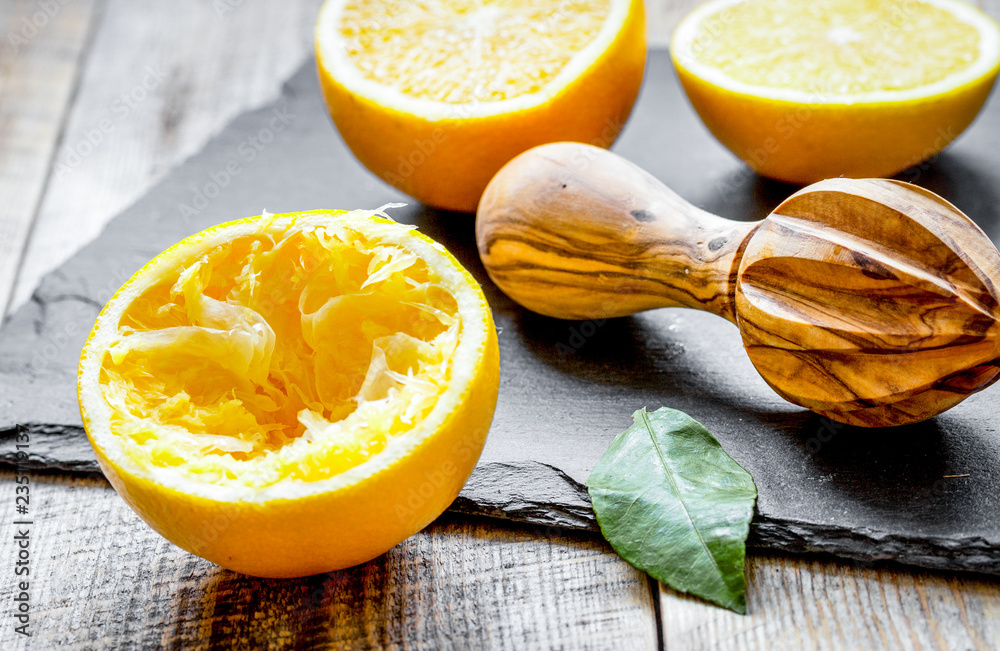 cut oranges in half and juicer on wooden background