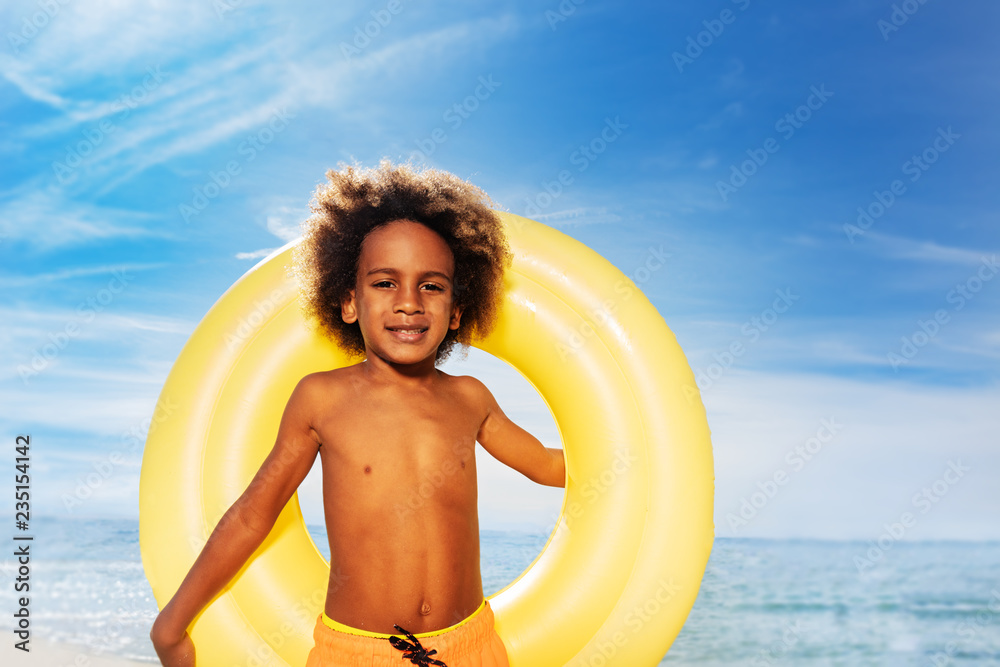 Cute African boy holding swim ring behind his back