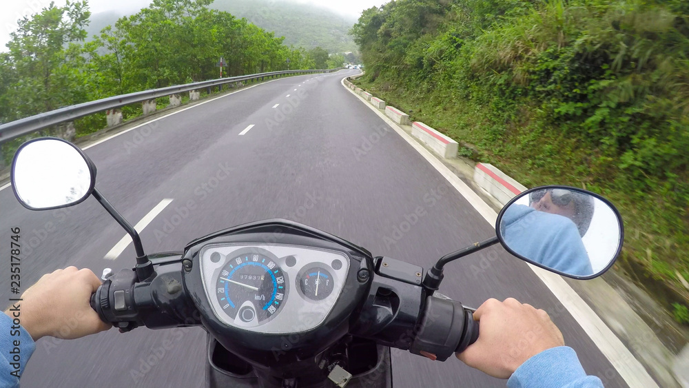 POV：骑着摩托车沿着穿过热带森林的空旷道路行驶。