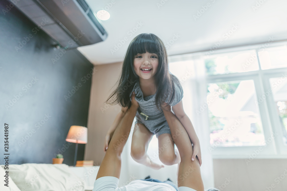 快乐的小女孩女儿和爸爸一起玩，骑爸爸回来，爸爸躺在家里的床上