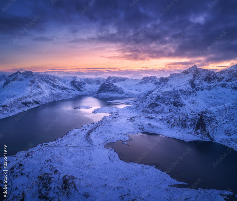 挪威罗弗敦群岛夜晚的雪山、大海和五颜六色的多云天空鸟瞰图。冬季