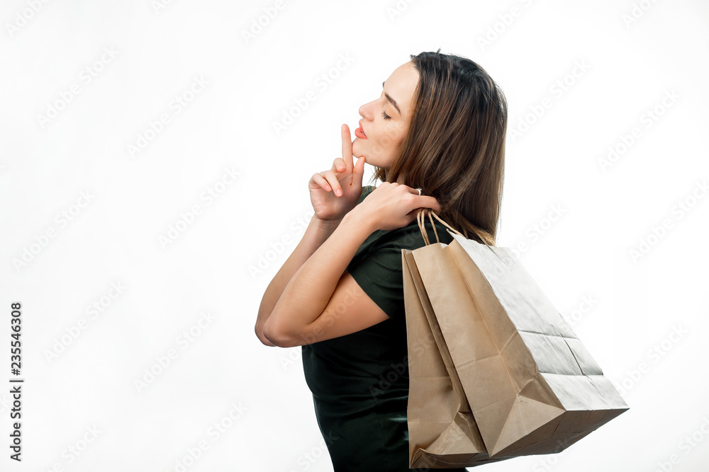 Dreamy cute girl with shopping paper bags posing on white background. Young attractive woman with cl