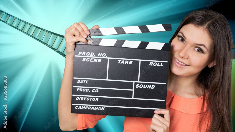 Young woman with cinema clapper smiling at camera