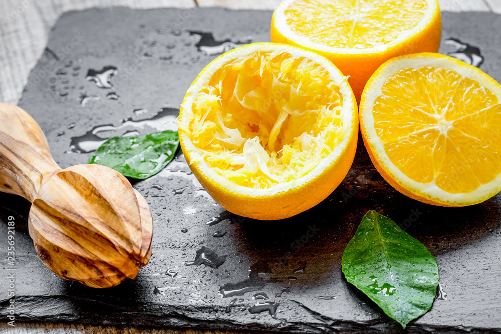 cut oranges in half and juicer on wooden background