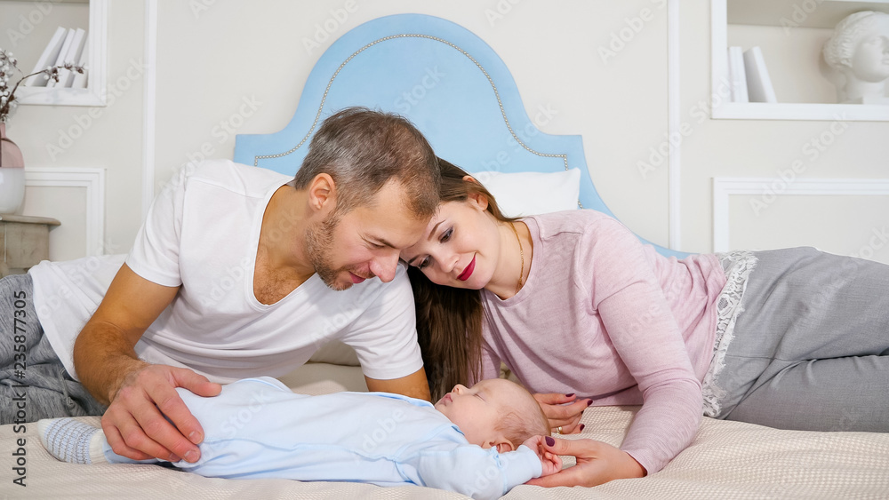 迷人的男人和女人看着卧室里熟睡的婴儿。