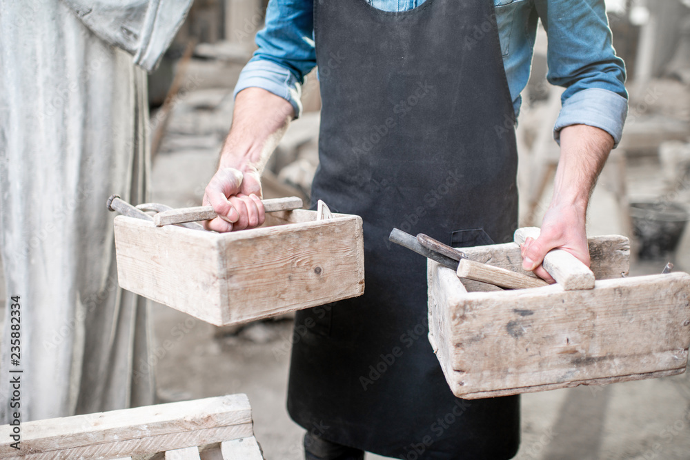 Sculptor with working tools in the studio. Close-up view with no face