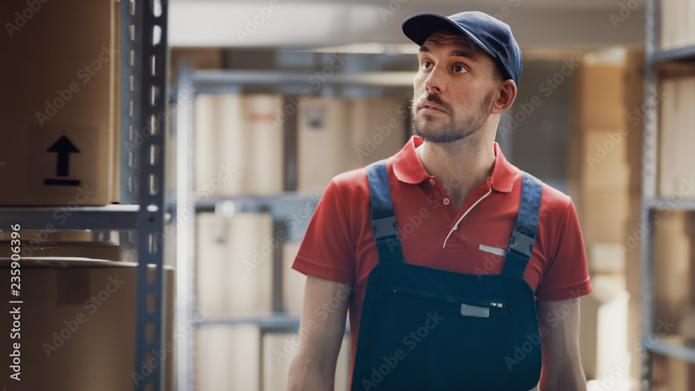 Worker Walks Through Warehouse Checking Stock, On the Shelves Standing Cardboard Boxes.