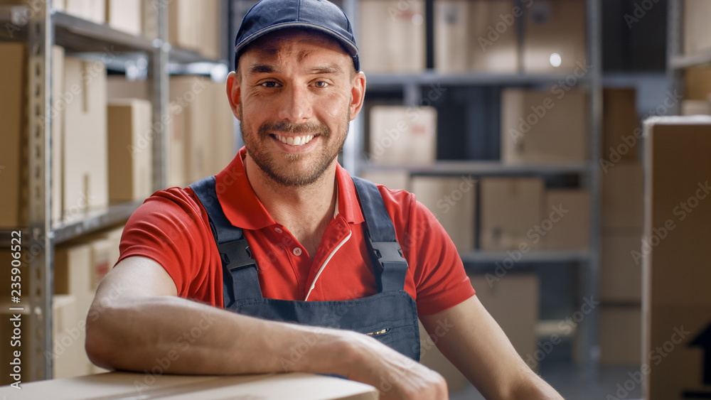 Smiling Worker Sitting at His Desk in the Warehouse.