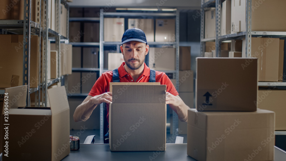 Professional Warehouse Worker Finishes Order, Sealing Cardboard Boxes Ready for Shipment. In the Bac