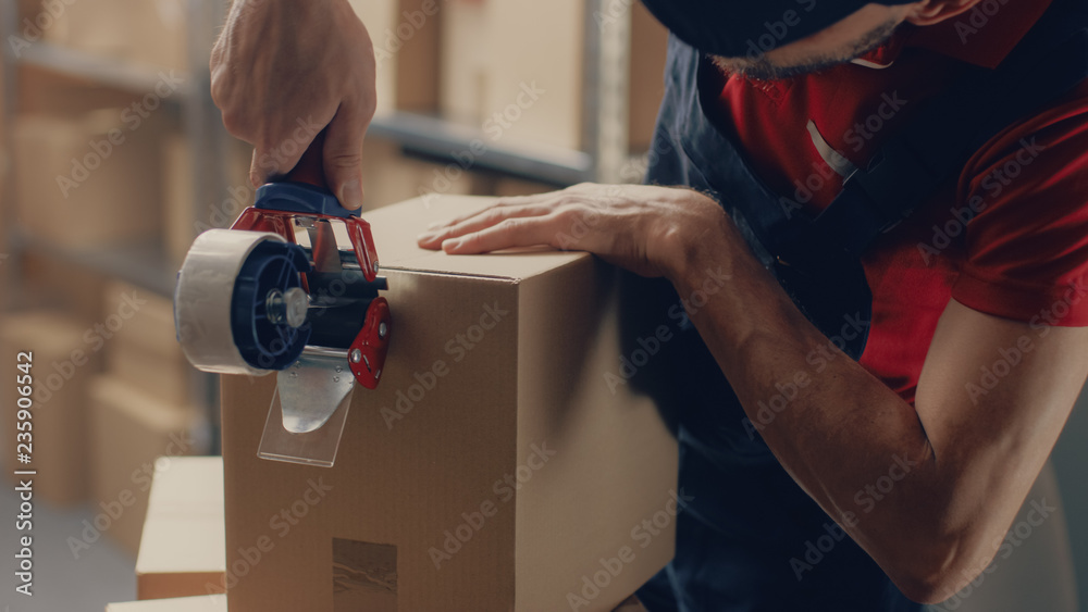 Warehouse Worker Packs Parcel and Sealing Cardboard Box Ready for Shipment. 