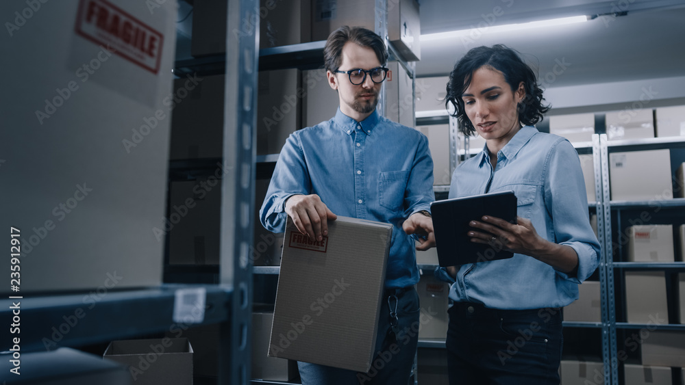 Female Inventory Manager Shows Digital Tablet Information to a Worker Holding Cardboard Box, They Ta