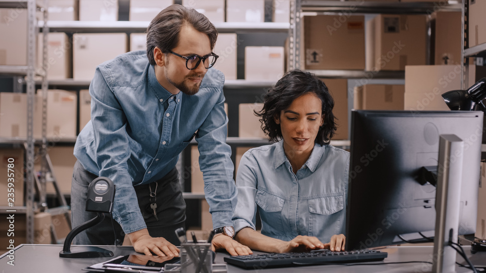 Male and Female Warehouse Inventory Managers Talking, Solving Problems, Using Personal Computer and 