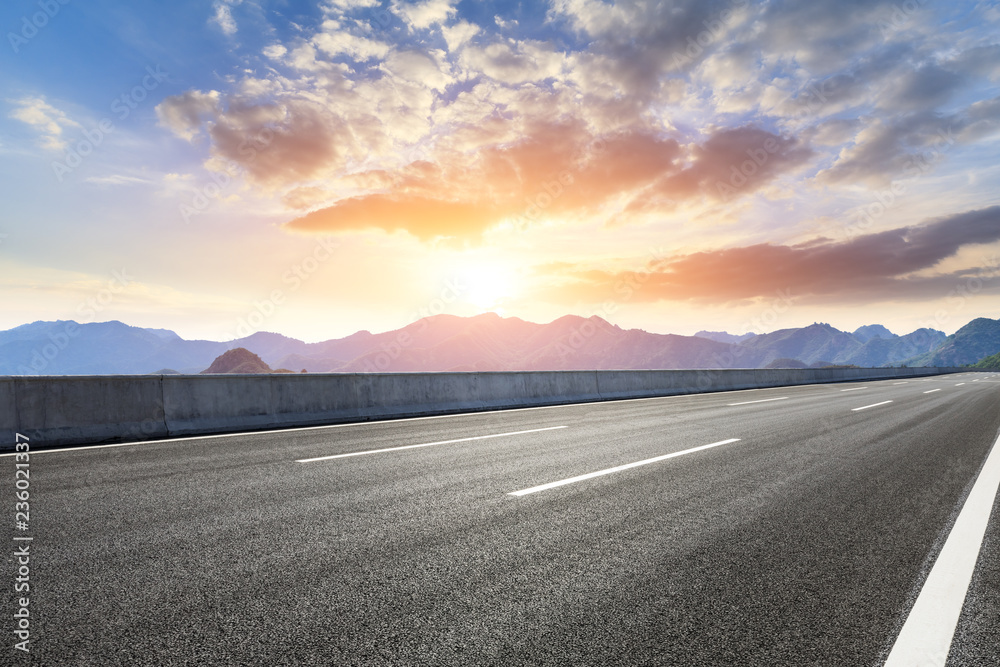 Asphalt road and mountains at beautiful sunset