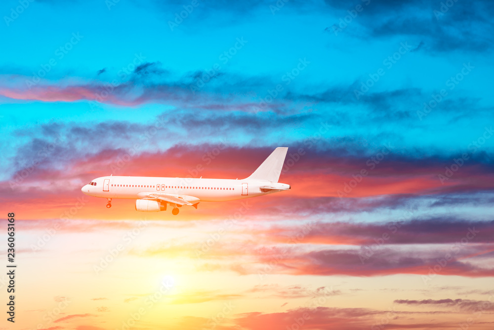 Airplane flying above dramatic clouds during sunset