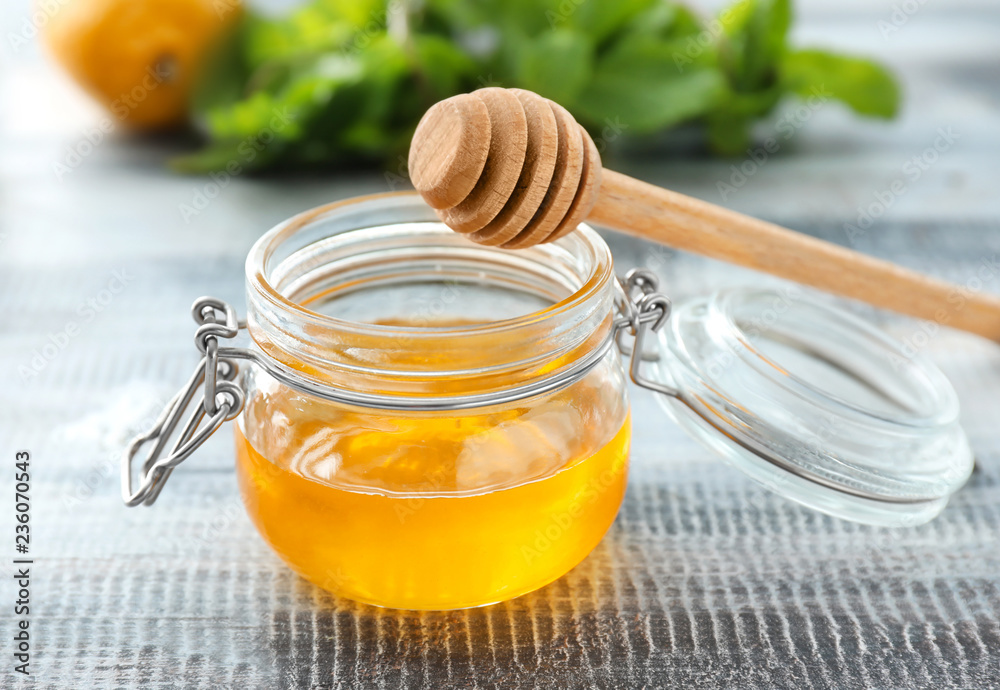 Glass jar with sweet honey on wooden table