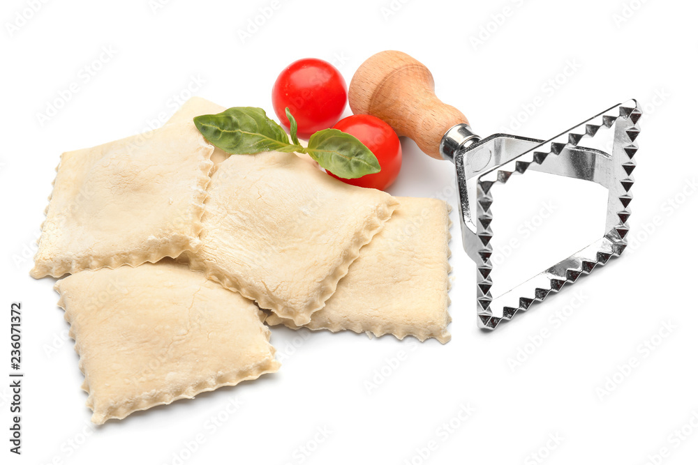 Raw ravioli, tomatoes and cutter on white background