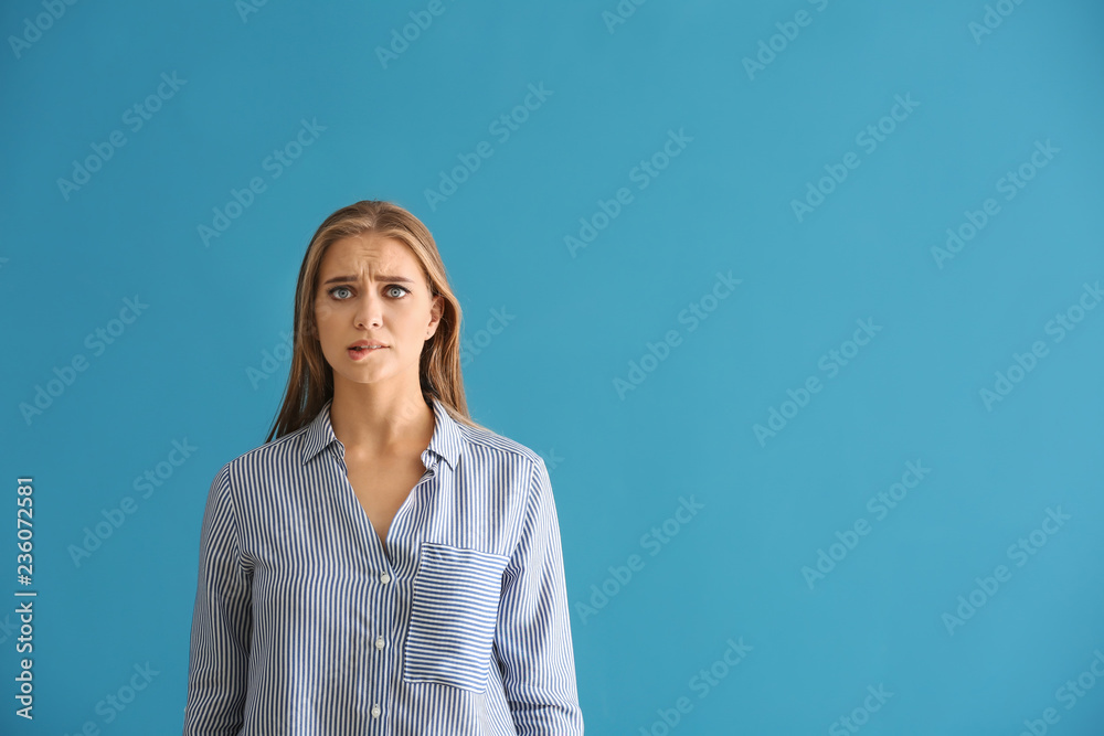 Emotional young woman after making mistake on color background