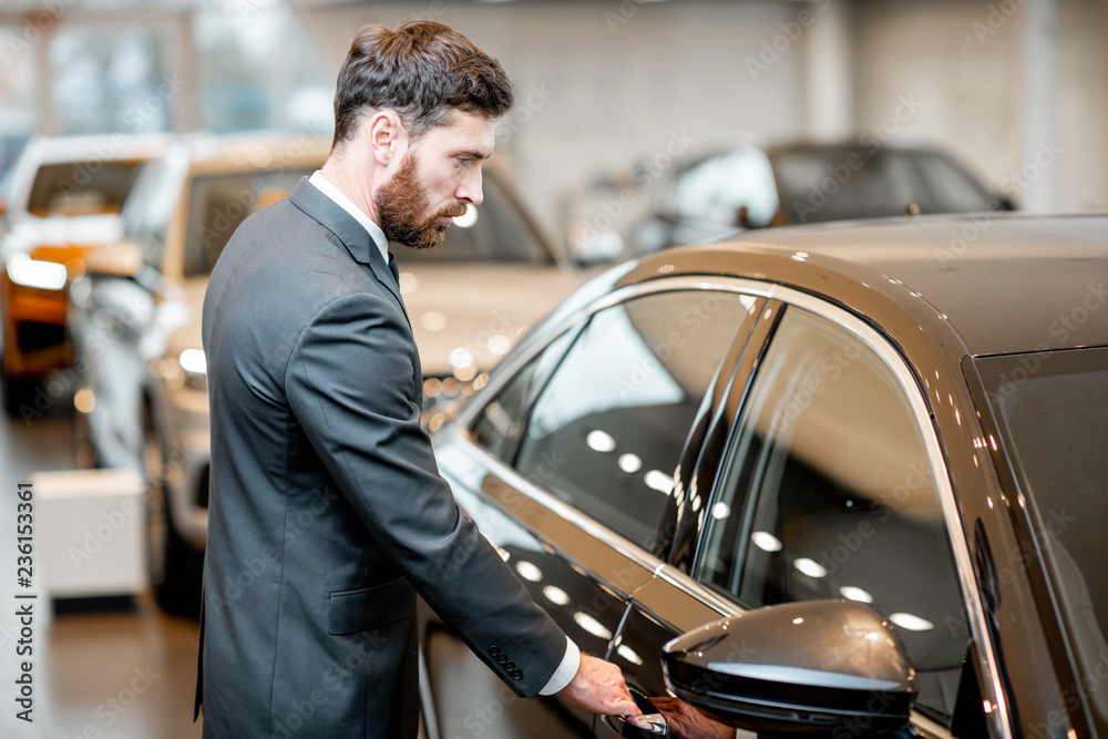 Elegant businessman choosing new luxury car in the showroom