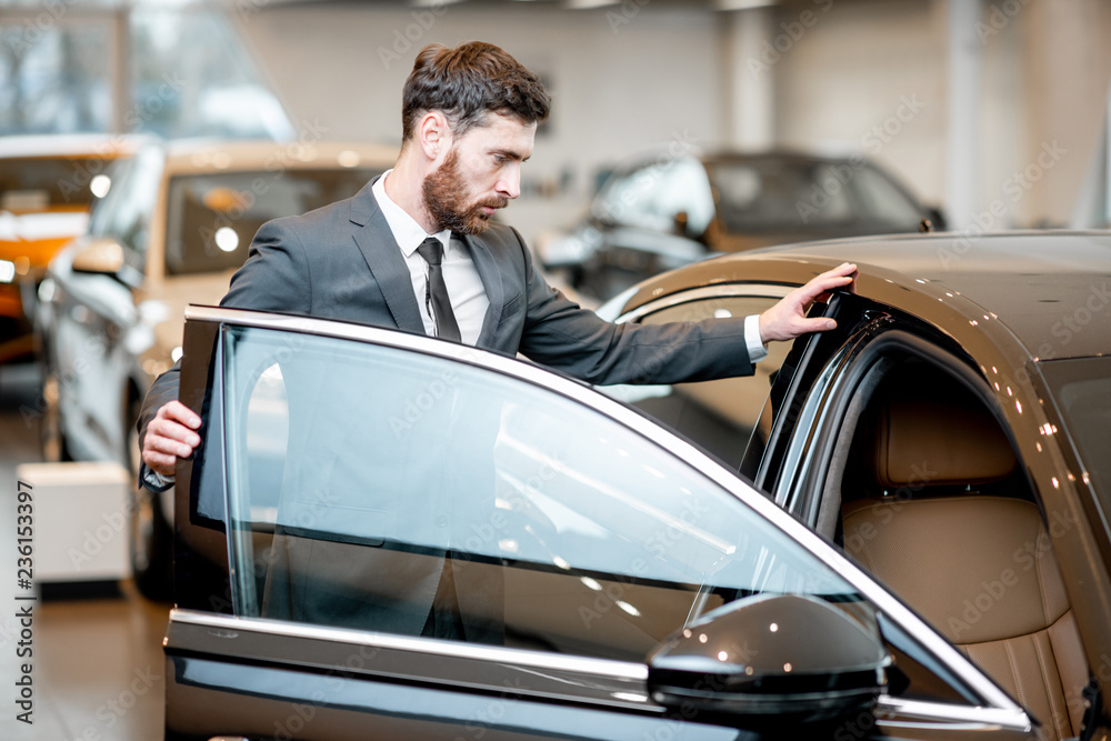 Elegant businessman choosing new luxury car looking at the car intreior in the showroom