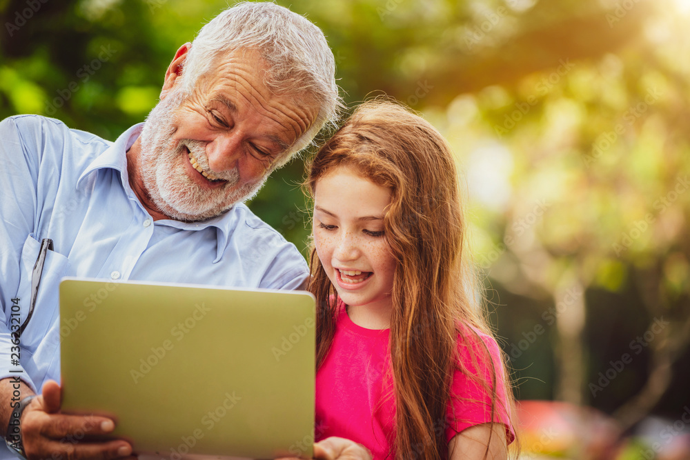 Happy family using laptop computer together in the garden park in summer. Kid education and family a