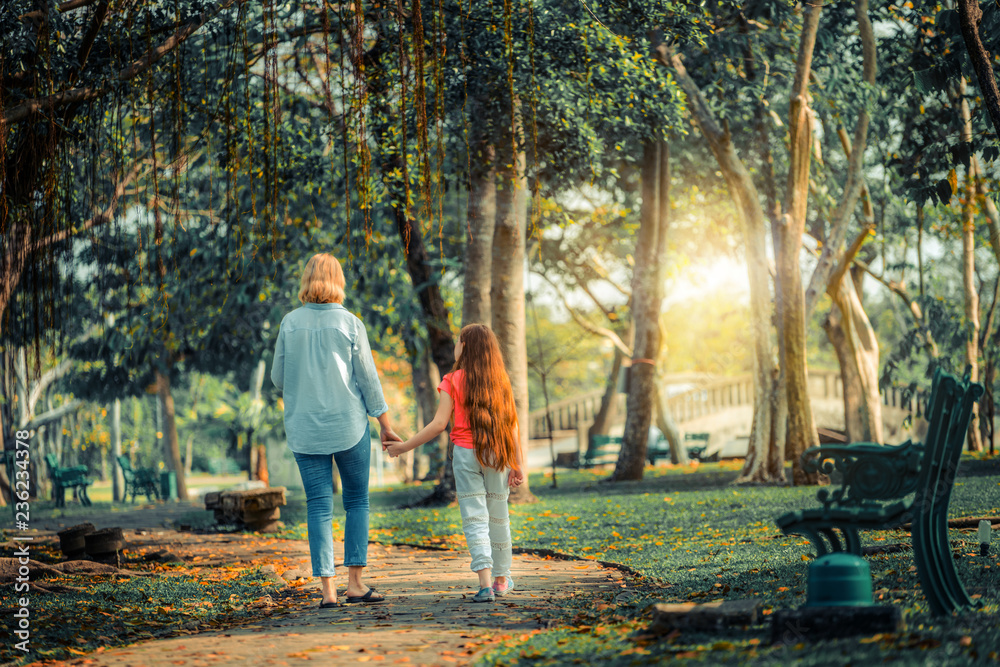 Relaxed happy mother and little kid daughter in outdoors public park. Parenthood and child concept.