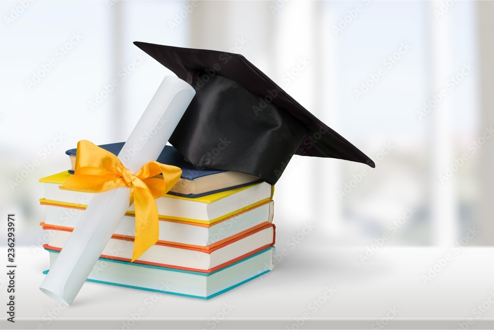 Graduation mortarboard on top of stack of books on  background