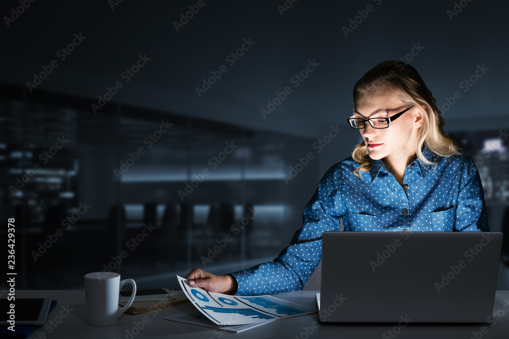 Beautiful blonde in dark office working on laptop and getting net access