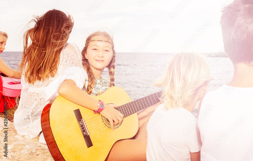 Young girl playing music on acoustic guitar