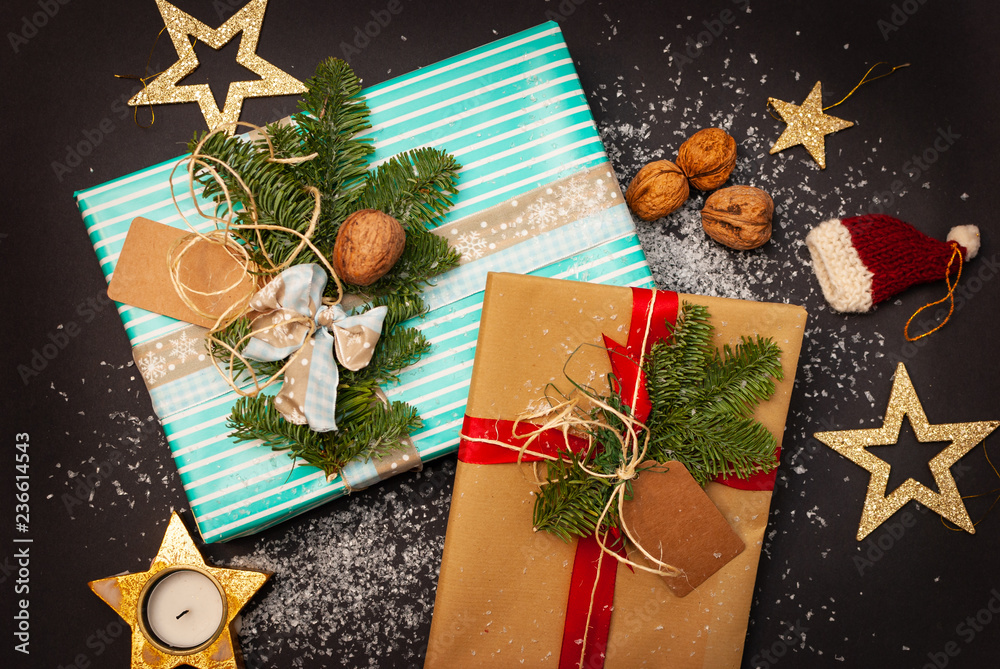 Flat-lay of two Christmas presents with some snow flakes, nuts, stars and a Christmas hut