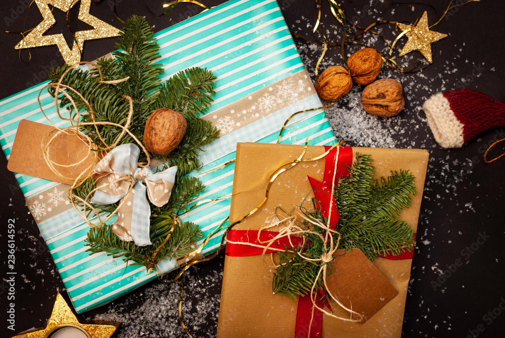 Flat-lay of two Christmas presents with some snow flakes, nuts, stars and a Christmas hut