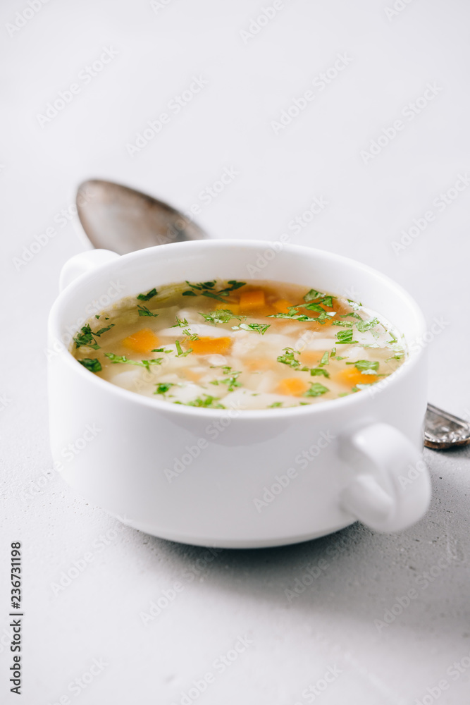 White bowl of homemade vegetable soup on concrete background